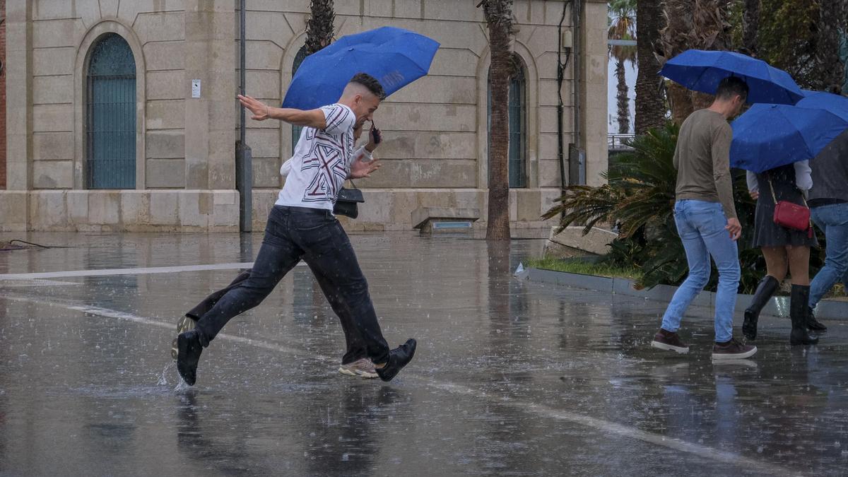 Una persona se protege de la intensa lluvia este viernes en Alicante.