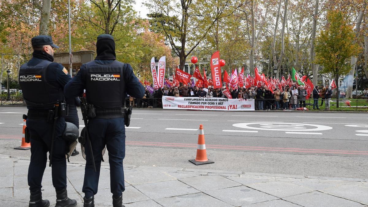 Dos agentes de Policía Nacional delante de una concentración para exigir la clasificación profesional de los técnicos superiores y de grado medio en el SNS, frente al Ministerio de Sanidad, a 11 de diciembre de 2024, en Madrid.