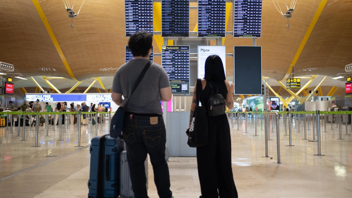 Varias personas miran las pantallas informativas en la T4 del Aeropuerto Adolfo Suárez Madrid-Barajas.