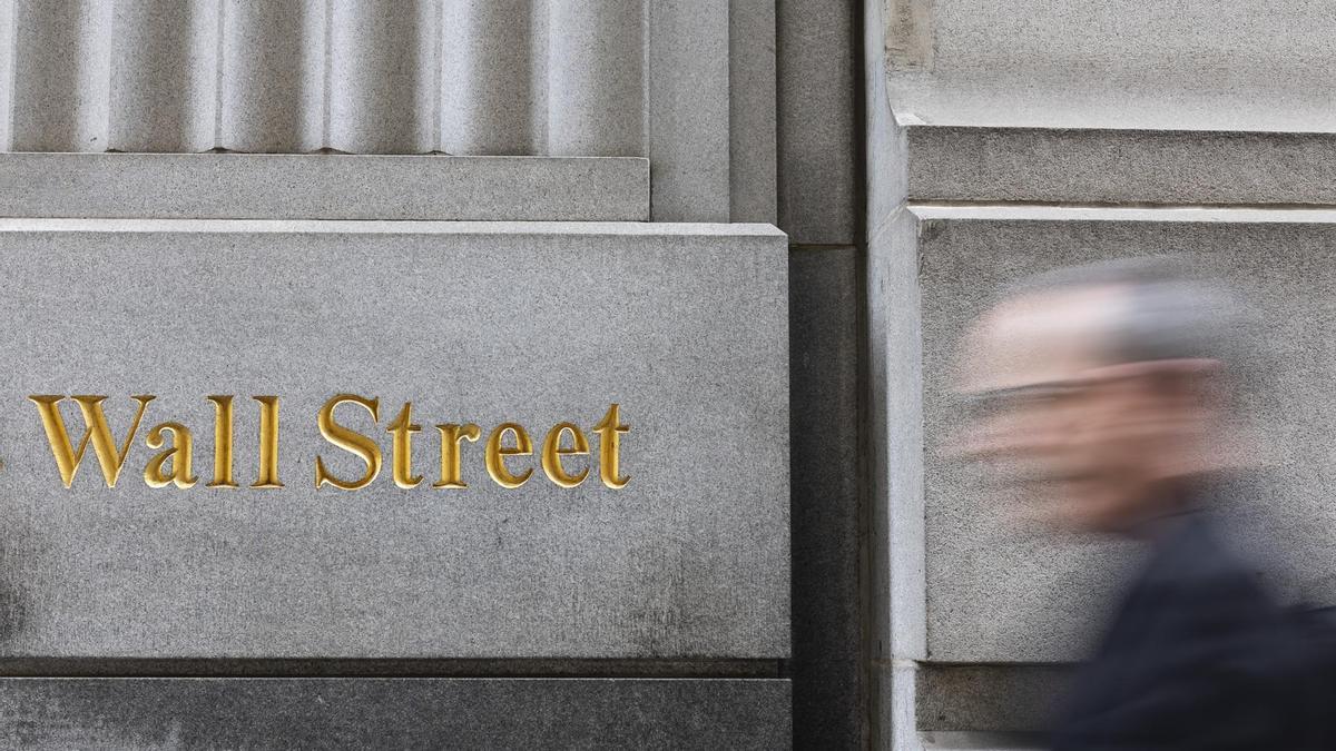 Un peatón pasa junto a un cartel de Wall Street cerca de la Bolsa de Valores de Nueva York.