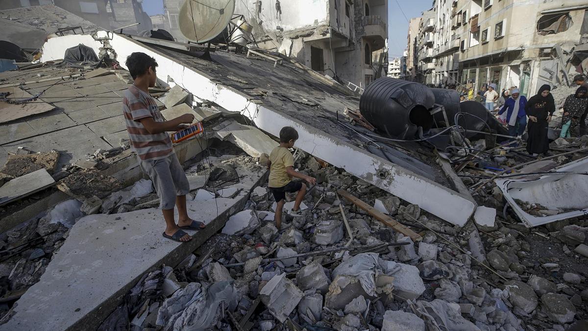 Niños palestinos caminan sobre la destrucción de un ataque israelí en Ciudad de Gaza.
