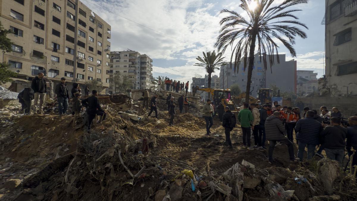 Miembros de la Defensa Civil de Gaza buscan cadáveres de entre los escombros de un edificio en la ciudad de Gaza este lunes