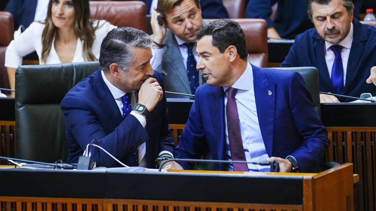 El consejero de Sanidad de la Junta de Andalucía, Antonio Sanz, conversa con el presidente Juanma Moreno tras su intervención en la sesión plenaria del Parlamento andaluz.