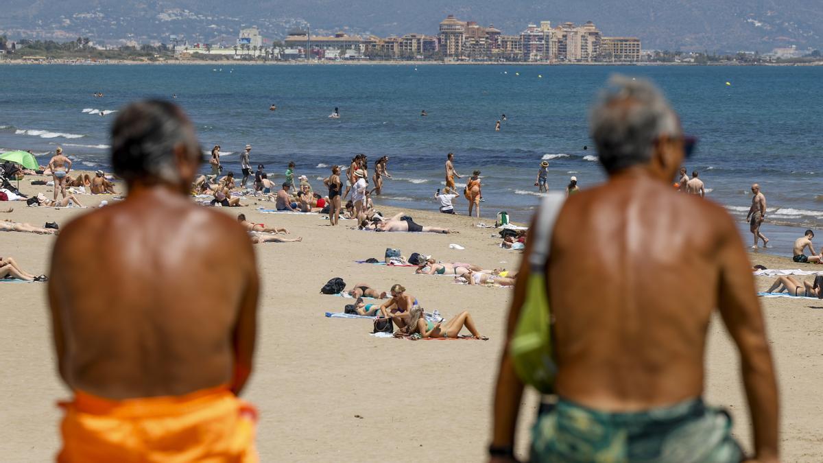 Dos personas contemplan la afluencia en la playa de la Malvarrosa durante la mañana de este martes en el que se esperan máximas de más de 30 grados en la provincia de Valencia.