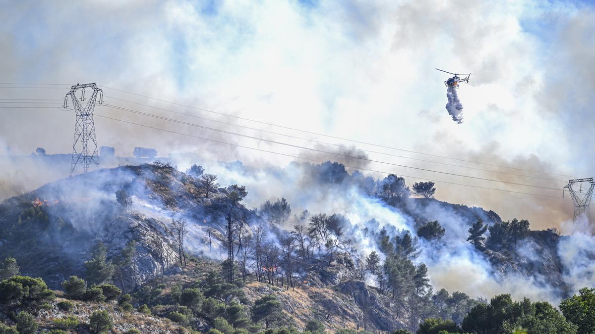 Un helicóptero lanza agua sobre un incendio forestal que se propaga rápidamente cerca de la ciudad de Marsella.