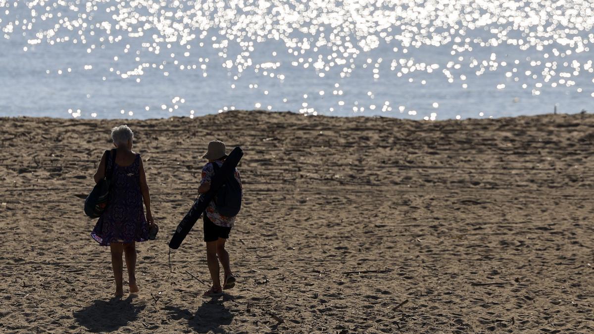 Dos personas se dirigen a la playa de El Saler durante este miércoles en el que el cielo de la Comunitat Valenciana.