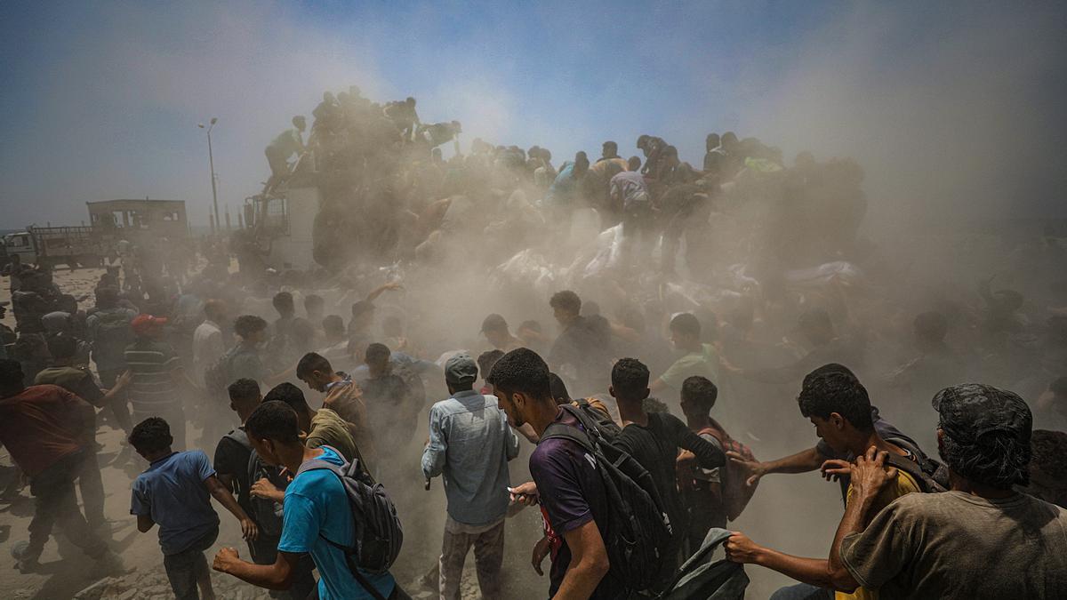Palestinos desplazados internos intentan recoger sacos de harina de un camión de ayuda humanitaria cerca de un punto de distribución de alimentos en Zikim.