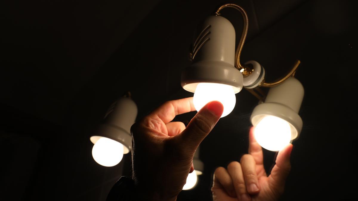 Una persona cambia la bombilla de una lámpara, el día en que el precio de la luz bate un récord histórico alcanzando los 124,45 euros por megavatio hora, a 30 de agosto de 2021, en Madrid.