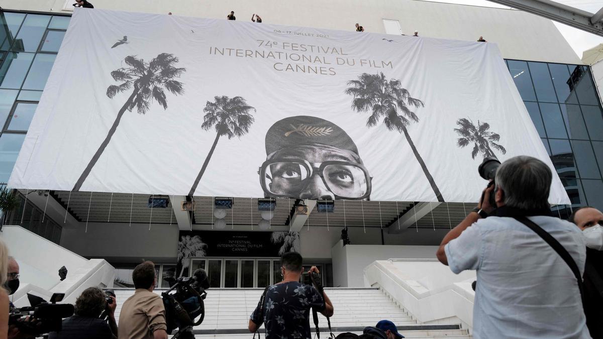 Archivo - Periodistas toman fotos mientras trabajadores instalan una pancarta gigante en el Palacio de Festivales y Congresos de Cannes, al sureste de Francia, dos días antes del inicio de la 74 edición del Festival de Cine de Cannes.
