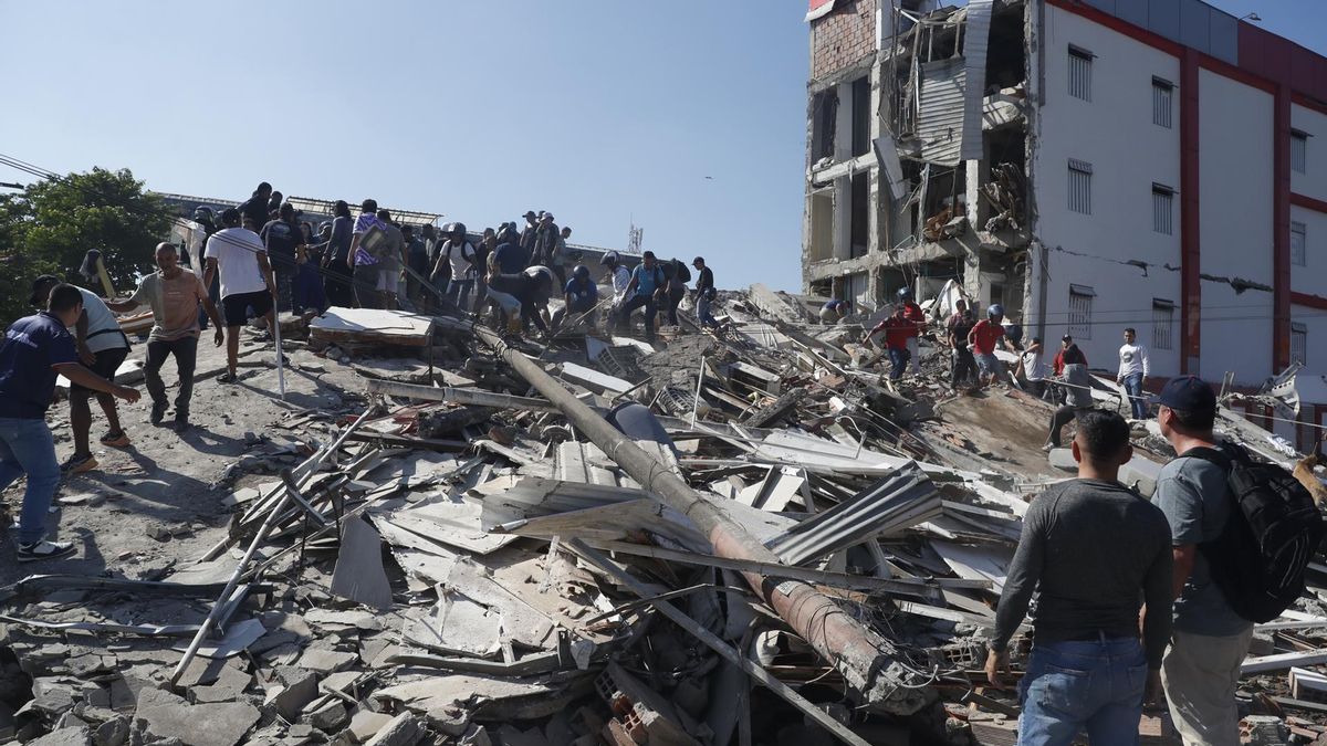 Personas caminan sobre los escombros de un edificio colapsado este lunes, en Cali (Colombia). Al menos 20 edificios sufrieron graves daños por consecuencia del terremoto de magnitud 7,4 que sacudió la mayor parte del país, con epicentro en la zona del Pacífico.
