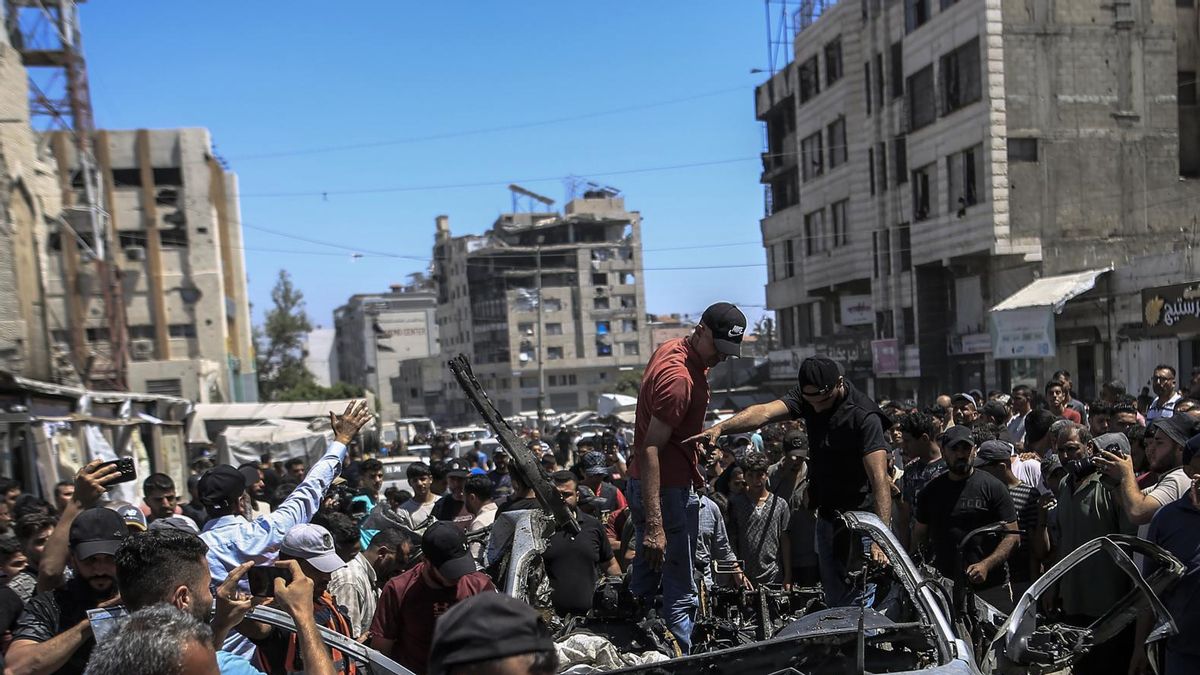 Palestinos inspeccionan un vehículo destruido tras un ataque aéreo israelí en la ciudad de Gaza.