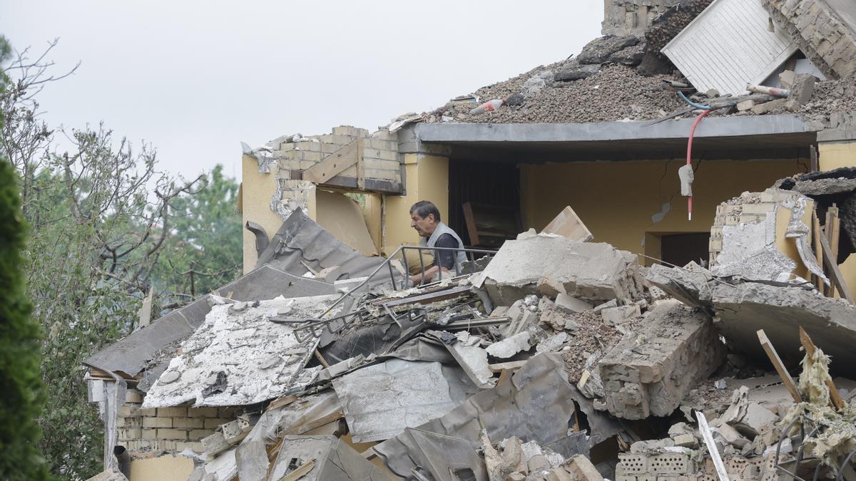 Un hombre limpia los escombros de una zona residencial alcanzada por un cohete tras un ataque ruso a una aldea cercana a Kiev.