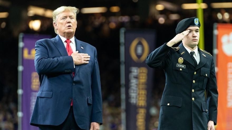 El presidente Donald Trump y la Primera Dama Melania Trump ponen la mano en el corazón por el himno nacional en el Campeonato Nacional de Playoffs de Fútbol Universitario.