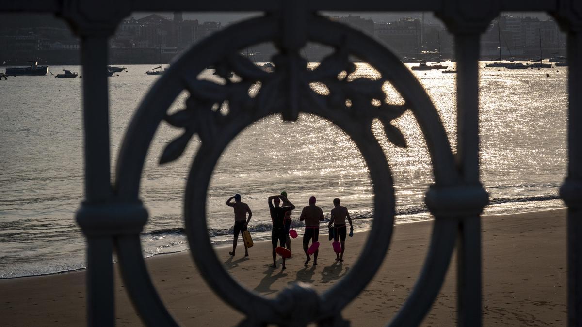 Varios nadadores se dirigen al agua en la playa de Ondarreta de San Sebastián a primera hora de este lunes.