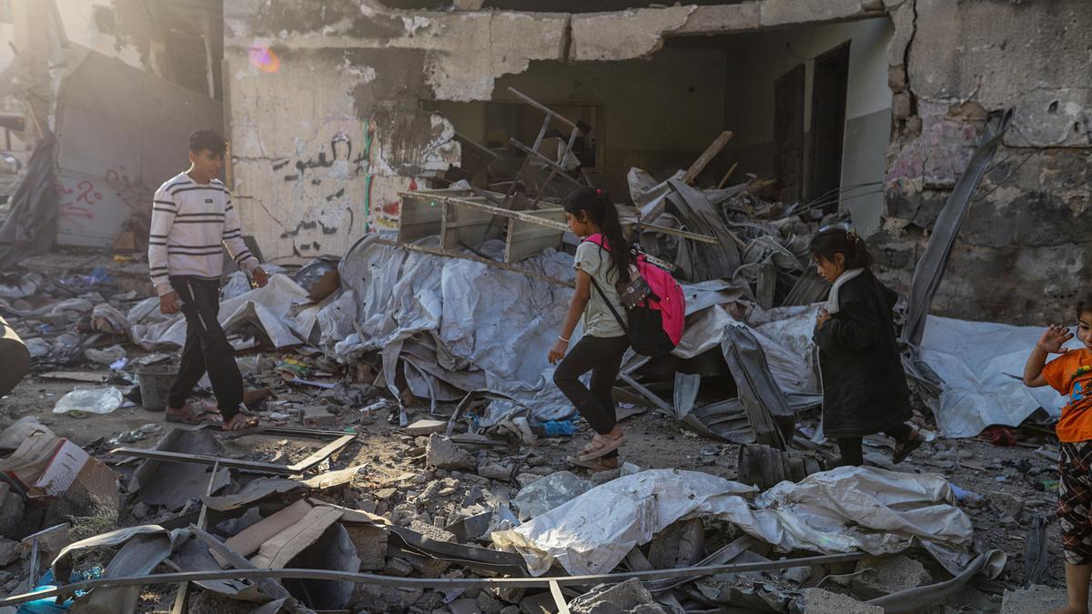 Varios niños palestinos caminan entre las ruinas de los edificios tras un ataque aéreo israelí en Al Nasr en la ciudad de Gaza.