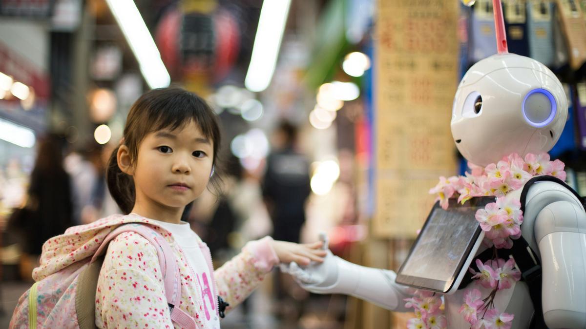 Una niña saluda a un robot en un mercado de Osaka (Japón).