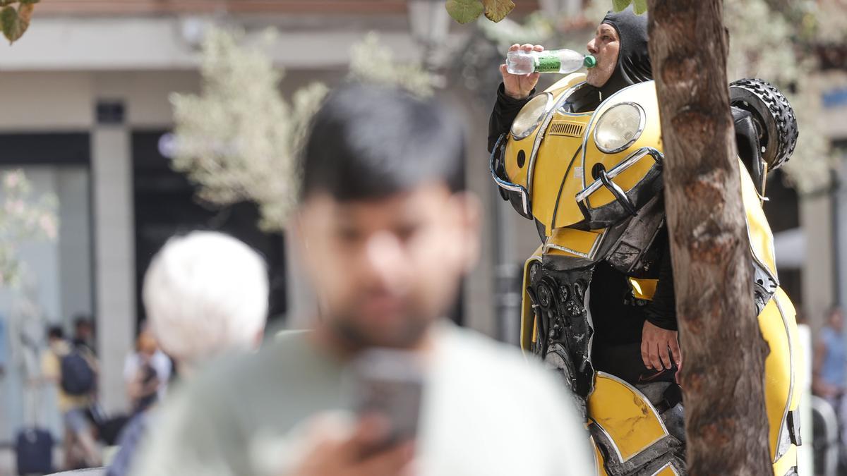 Un artista callejero se refresca bebiendo agua, este mediodía en la plaza del Ayuntamiento de València.