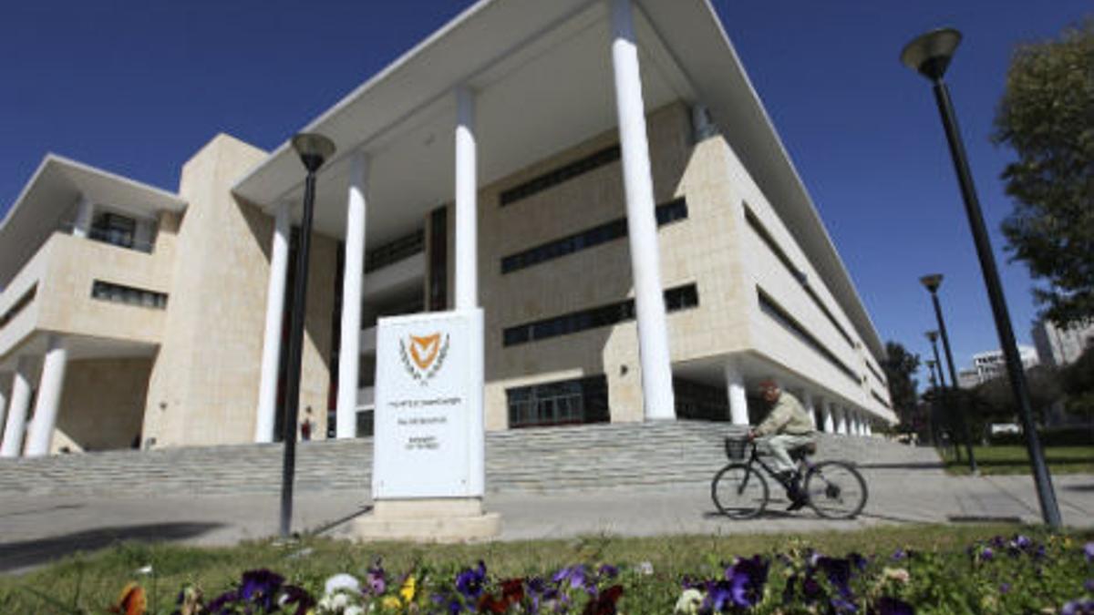 Un hombre pedalea por las afueras del Ministerio de Finanzas de Nicosia.