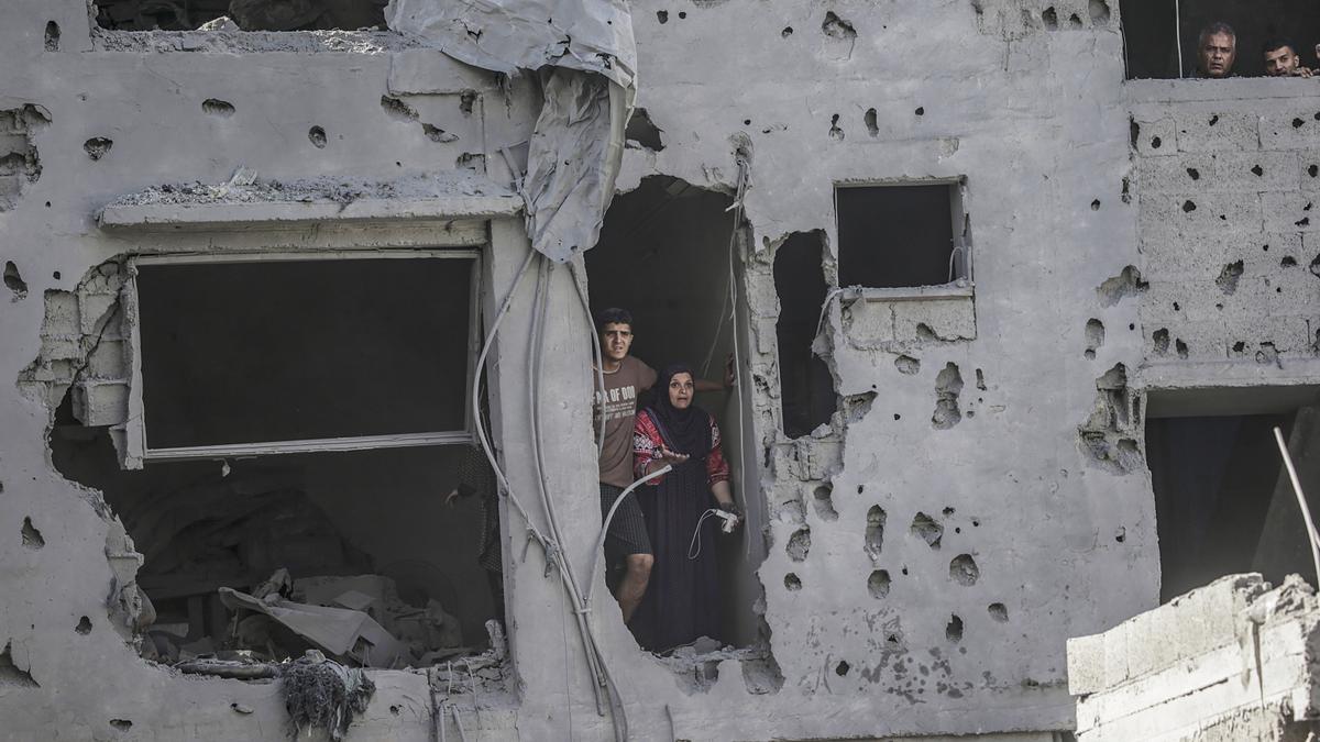 Residentes observan desde un edificio destruido tras un ataque aéreo israelí en el campo de refugiados de Al Shatea, Gaza.