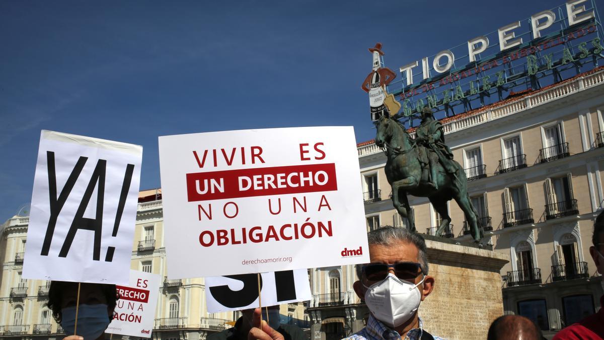 Un grupo de personas se reúne sosteniendo pancartas y carteles durante la concentración de la asociación Derecho a Morir Dignamente (DMD) en la Puerta del Sol, a 25 de junio de 2021.