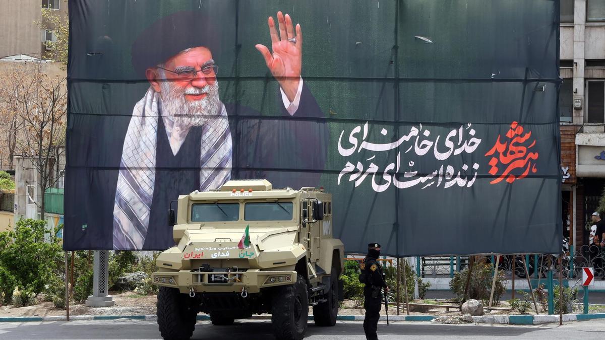 Un miembro de las fuerzas de seguridad iraníes monta guardia junto a una pancarta en honor al exlíder supremo iraní Ali Khamenei.