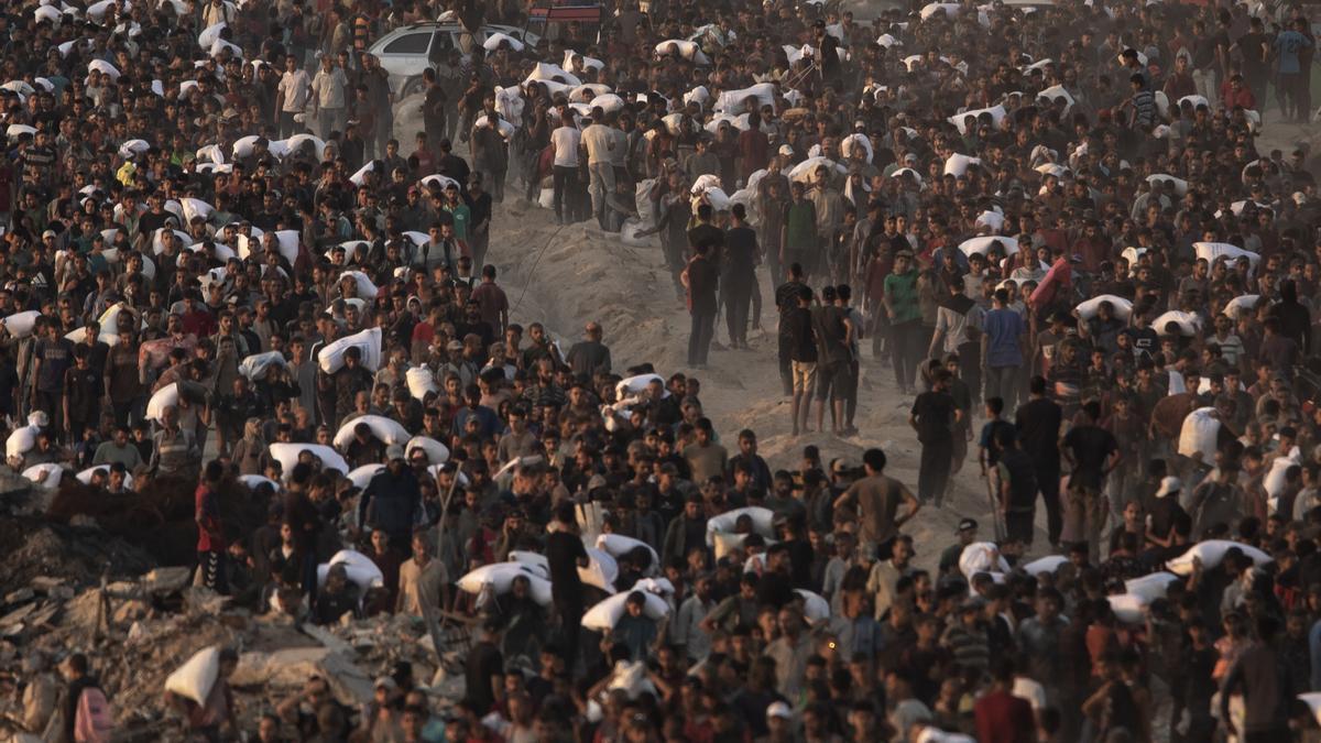 Palestinos desplazados llevan bolsas de harina por la calle Rashid en el oeste de la ciudad de Gaza.
