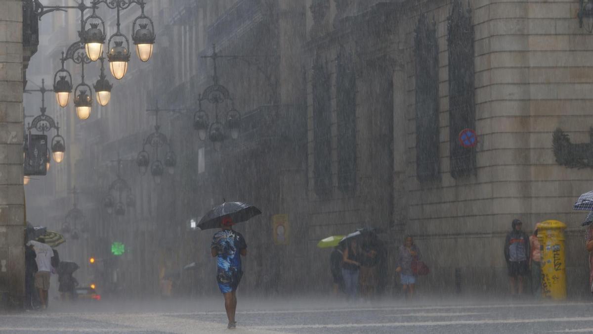 Personas se protegen de la lluvia en el centro de Barcelona.