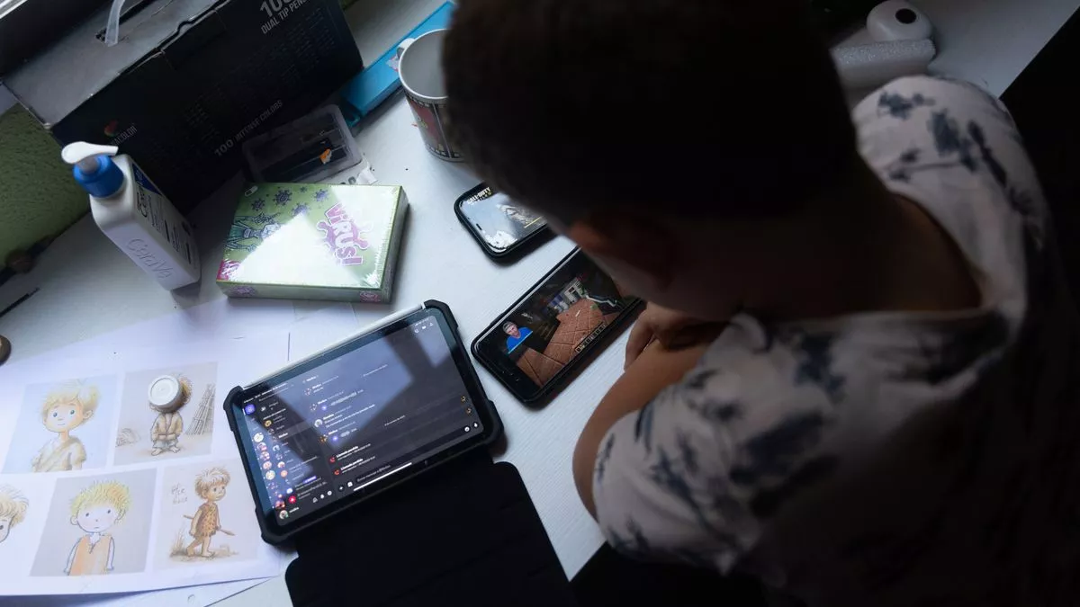 Un niño usa el teléfono móvil y una tablet (archivo)
