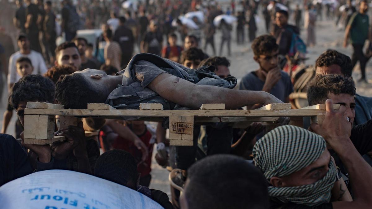 Palestinos cargan el cuerpo de un hombre asesinado por Israel cuando intentaba conseguir un saco de harina