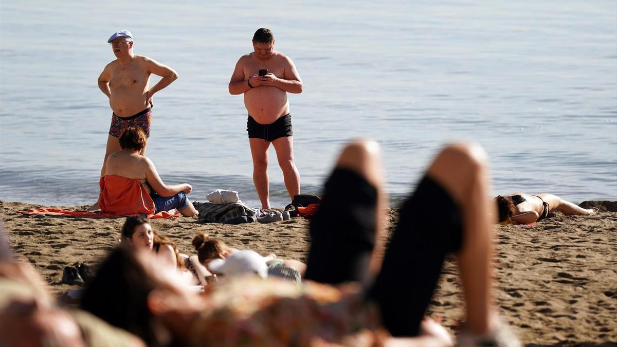Varias personas disfrutan tomando el sol en la playa de la Malagueta, en diciembre de 2023.