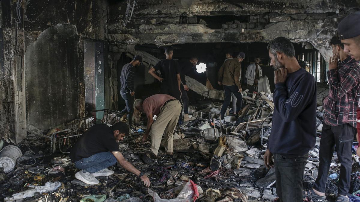 Palestinos  inspeccionan los escombros de la escuela Al Jerjawi tras un ataque aéreo israelí en el barrio de Al Daraj de la ciudad de Gaza.