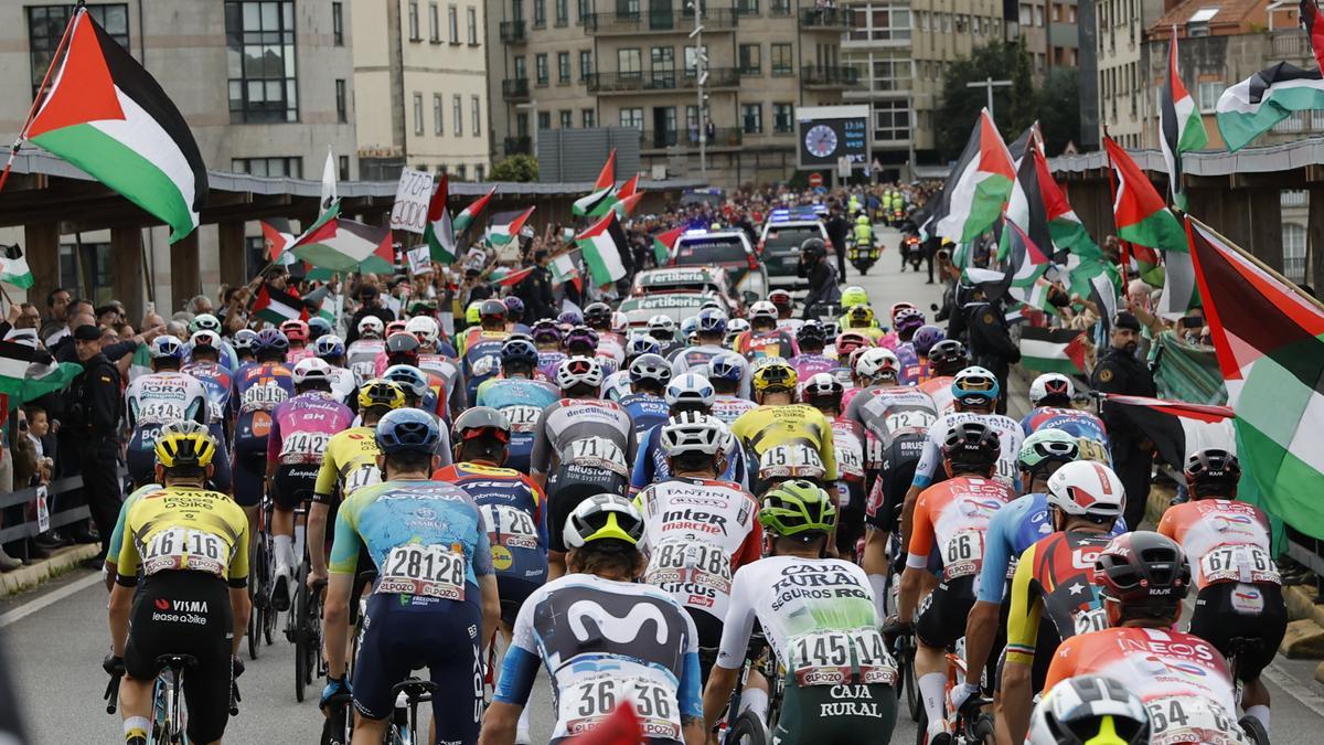 El pelotón pasa ante la protesta propalestina durante la etapa 16 de la Vuelta Ciclista a España.