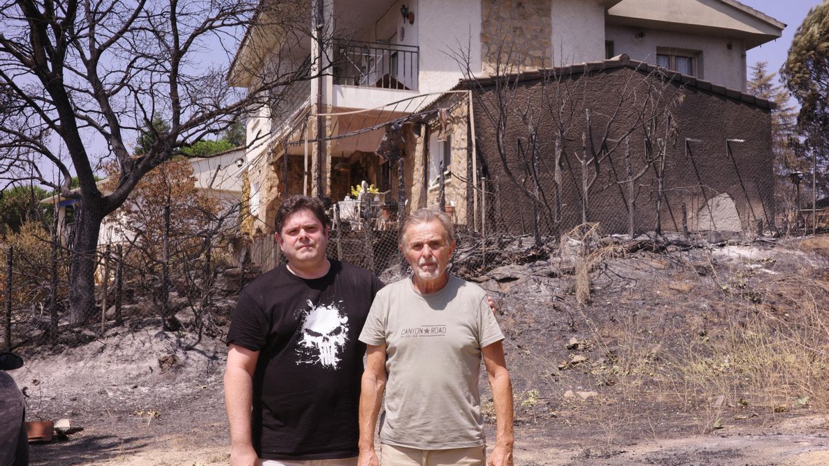 Agustín Muñoz (derecha) y su hijo posan frente a su casa de Pelayos de la Presa, que ha quedado parcialmente calcinada.