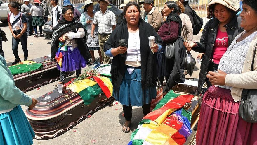 Un grupo de mujeres realiza una ceremonia ante los féretros de varios de los fallecidos tras los disturbios con las fuerzas del orden